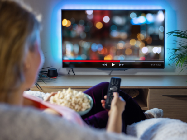 Woman watching tv while eating popcorn